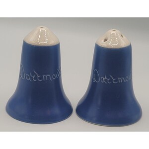 May include: A pair of blue ceramic salt and pepper shakers. Each shaker has a white top with holes and the word "Dartmouth" in cursive script. The shakers have a bell-like shape.