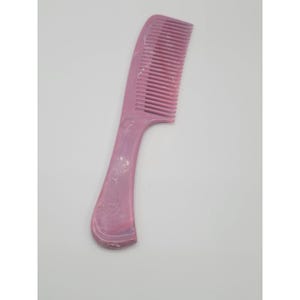 May include: A pink comb with a handle and fine teeth. The comb is made of a solid, smooth material and has a curved handle for easy grip. The comb is designed for hair care and styling.