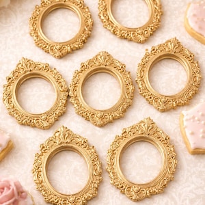 May include: Seven ornate, gold-colored picture frames with intricate detailing are arranged on a patterned surface. The frames are circular with decorative edges and a central opening. The image also includes decorated cookies.