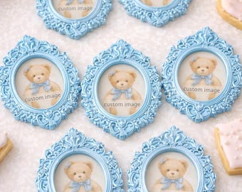 May include: Light blue ornate picture frames with a teddy bear image and the text "custom image". The frames are arranged on a white surface with flowers and cookies.