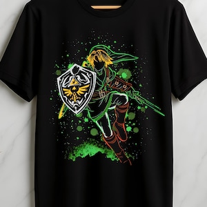 Peut inclure: T-shirt noir avec un graphisme vert néon et jaune d'un personnage avec un bouclier et une épée. Le motif a un effet d'éclaboussure avec des accents verts. Le t-shirt est suspendu à un cintre en bois.