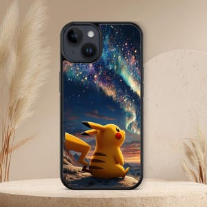 Peut inclure: Coque de téléphone noire avec un personnage Pikachu jaune regardant une scène d'aurore boréale colorée. Le design comprend une illustration détaillée du ciel nocturne avec des étoiles et des couleurs vives.