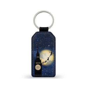 Puede incluir: Un llavero con un diseño de cielo nocturno, con el Big Ben y siluetas de Peter Pan y los niños Darling volando hacia la luna. Tiene un anillo plateado y una correa negra.