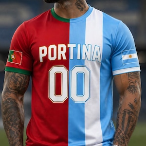 Pode incluir: Uma camisola de futebol de duas cores, vermelha e azul clara, com a palavra "PORTINA" e o número "00" estampados na frente. A camisola apresenta as bandeiras de Portugal e da Argentina nas mangas. A camisola é usada por uma pessoa.