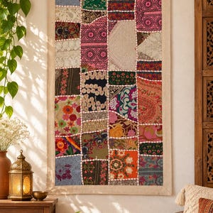 May include: A rectangular wall hanging featuring a patchwork design of various fabric squares. The textile displays a diverse array of colors, including pink, green, orange, and blue, with intricate embroidery, lace, and floral patterns throughout.