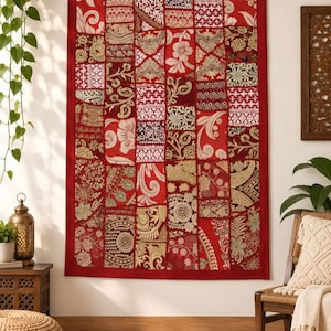 May include: A rectangular wall hanging featuring a patchwork design of various red, gold, and white fabric squares. The textile displays a mix of intricate floral, paisley, and geometric patterns with embroidered details and a solid red border.
