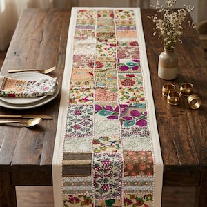 May include: A rectangular table runner featuring a patchwork design of various embroidered fabric squares in vibrant colors including pink, green, yellow, and red, with intricate floral patterns, lace accents, and metallic thread detailing.