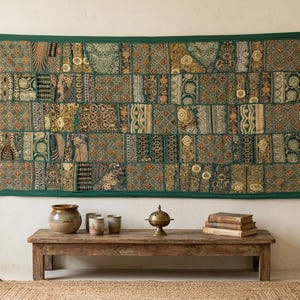Peut inclure: Une tenture murale rectangulaire composée d'un patchwork de panneaux en tissu vert, doré et marron, ornés de broderies complexes, de fils métalliques et de motifs floraux et géométriques variés, bordée d'une bordure vert foncé unie.
