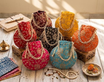 Könnte beinhalten: Eine Sammlung von sechs runden Beuteltaschen mit Kordelzug in Rot, Kastanienbraun, Schwarz, Gelb, Orange und Türkis. Jede Tasche ist mit aufwendigen goldenen Blumenstickereien und einem dekorativen Henkel aus mehreren Strängen weißer Perlen versehen.