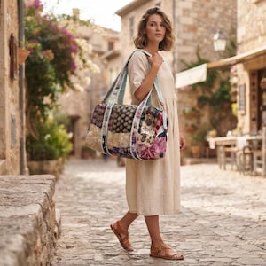 Peut inclure: Un grand sac de voyage au design patchwork composé de divers motifs floraux et géométriques dans des tons rose, bleu, marron et crème. Le sac présente des sangles en tissu bleu clair et une forme rectangulaire, porté à l'épaule par une personne.