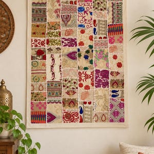 May include: A rectangular wall hanging featuring a patchwork design of various fabric squares. The textile displays a multitude of colours including red, blue, pink, green, and gold, with intricate floral, paisley, and geometric embroidery patterns.