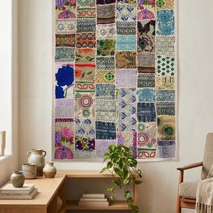 May include: A rectangular wall hanging featuring a patchwork design composed of numerous small fabric squares. Each square displays distinct patterns, including floral motifs, geometric shapes, and intricate embroidery in various colors.