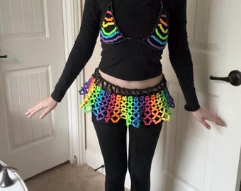 Peut inclure: Un haut et un legging noirs, associés à un haut de bikini arc-en-ciel perlé et à une jupe assortie. La jupe et le haut de bikini présentent un éventail de couleurs vives, notamment le rouge, l'orange, le jaune, le vert, le bleu et le violet.