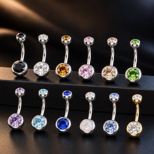 Op de afbeelding: Een collectie van twaalf gebogen navelpiercings met gepolijste zilverkleurige metalen staafjes en zettingen. Elk sieraad is voorzien van een grote ronde gefacetteerde edelsteen aan de onderkant en een kleinere bijpassende steen aan de bovenkant.