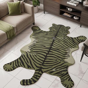 May include: A green and black rug in the shape of a tiger. The rug has a zebra stripe pattern and is placed on a white tiled floor. The rug is in a living room setting with a sofa, pillows, and a side table.