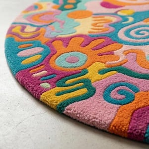 Vibrant pink teal orange round doodle hand tufted wool rug on light wood floor in a maximalist bright living room.