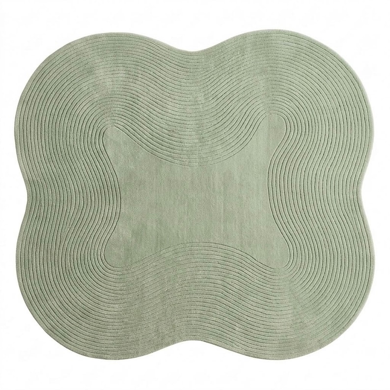 May include: A sage green area rug with a distinct four-lobed, clover-like shape. The surface features a series of concentric, wavy, carved lines that follow the outer contour of the rug, creating a textured, rippled effect across the entire piece.
