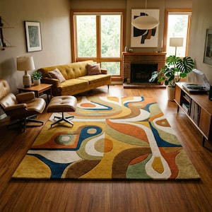 May include: A living room with a retro aesthetic, featuring a mustard-coloured sofa, a patterned rug with blue, orange, and yellow tones, and a brown leather chair. The room includes a fireplace, large windows, and a wooden entertainment unit.