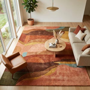 May include: A large, colorful area rug with an abstract landscape design in shades of orange, brown, yellow, and green. The rug is placed in a living room setting with a sofa, armchair, and coffee table. The rug's dimensions are not visible.