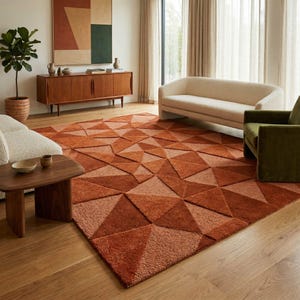 May include: A geometric patterned area rug in shades of orange and brown dominates the room. The rug's design features a repeating pattern of triangles, creating a textured surface. The rug is placed on a wooden floor, and the room includes furniture and decor.