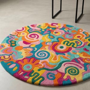 Vibrant pink teal orange round doodle hand tufted wool rug on light wood floor in a maximalist bright living room.