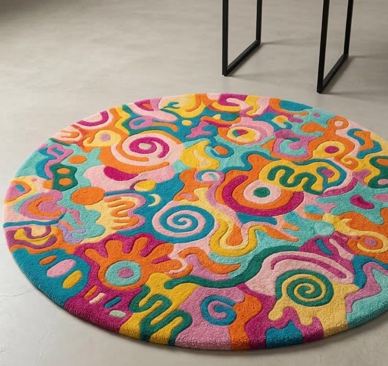 Vibrant pink teal orange round doodle hand tufted wool rug on light wood floor in a maximalist bright living room.