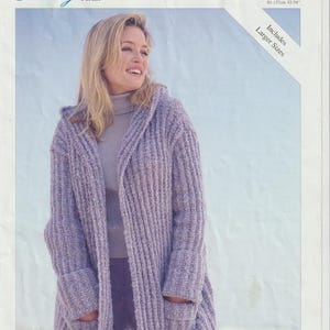 May include: A woman wearing a lavender hooded cardigan with pockets. The cardigan is part of a knitting pattern from Sirdar, labeled "Eternity Aran." The pattern includes larger sizes, with measurements from 32-54 inches.