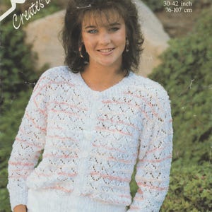 May include: A woman wearing a white, open-knit cardigan with pink horizontal stripes. The cardigan has a button-up front and long sleeves. The image includes text that reads "Robin Creates the look" and "Dash 30-42 inch".