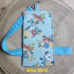 May include: A light blue phone case with a bird and floral pattern. The case has a blue strap and a key ring attachment. The text "Blue Bird" is printed on the bottom. The case is approximately 7 inches tall and 4 inches wide.