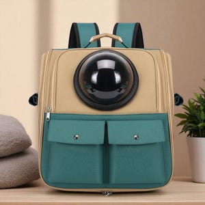 Puede incluir: Mochila transportadora para mascotas en color beige y verde azulado con una ventana transparente en forma de burbuja. Cuenta con dos bolsillos delanteros verde azulado, un asa superior y correas ajustables.