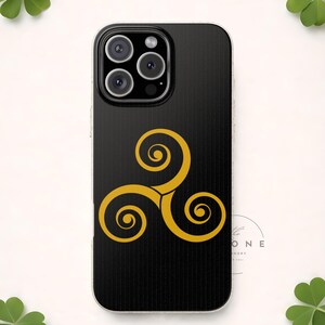 May include: Black iPhone case featuring a gold triskele design. The triskele, a Celtic symbol, is composed of three interconnected spirals. The case has a glossy finish and is designed to fit a smartphone.