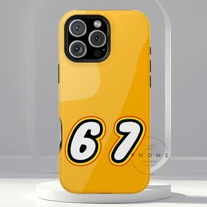 Könnte beinhalten: Gelbe Handyhülle mit der Nummer "67" in einer kräftigen, verspielten Schriftart. Die Hülle hat eine glänzende Oberfläche und ein schwarzes Kameramodul. Das Design erinnert an ein beliebtes Bausteinspielzeug. Das Logo The Phone Foundry ist sichtbar.