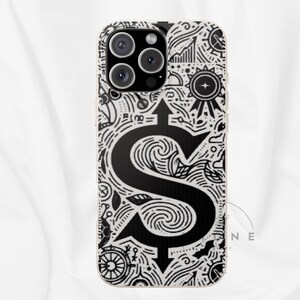 May include: A phone case with a black and white design. The case features a large black dollar sign with an arrow, surrounded by intricate line art. The case has a gold-colored border and a camera cutout.