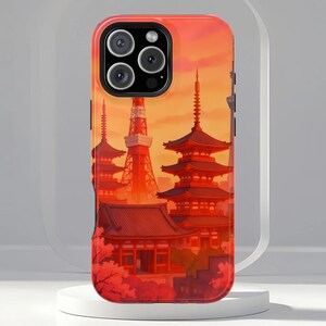 May include: A phone case with a vivid illustration of Japanese pagodas and a tower set against a sunset. The case is mainly red and orange, with detailed architectural features. The case has a glossy finish and a camera cutout.