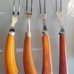 May include: Four vintage metal forks with brown plastic handles. The forks have three tines each and are in good condition.