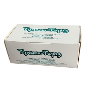 May include: A white rectangular box with teal text, including "Тунеыш-Тараз". The box contains school chalk, with text in a foreign language. The box is on a white background.