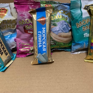 May include: A selection of packaged products with Russian text, including "Sea Clay" and "Bentonite Bar". The packaging is in various colours such as gold, blue, pink, and green. The products appear to be cosmetic or skincare items.