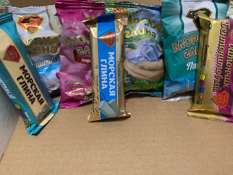 May include: A selection of packaged products with Russian text, including "Sea Clay" and "Bentonite Bar". The packaging is in various colours such as gold, blue, pink, and green. The products appear to be cosmetic or skincare items.