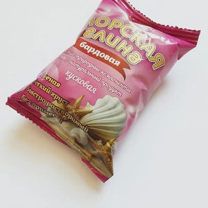 May include: A pink package of "Morskaya Glina" candy, featuring a seashell and starfish design. The package has Russian text, including "natural ingredients" and "easily soluble."
