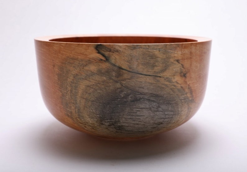 May include: A large, wooden bowl with a natural, brown and gray wood grain pattern. The bowl is round and has a smooth, polished finish.