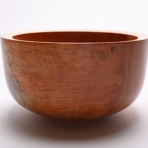 May include: A large, wooden bowl with a natural, light brown finish. The bowl is round and has a smooth, polished surface.