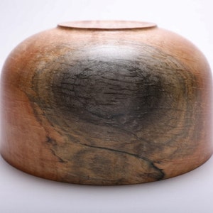 May include: A wooden bowl with a dark brown and light brown wood grain pattern. The bowl is round and has a smooth, polished finish.