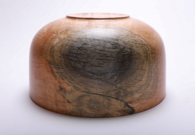 May include: A wooden bowl with a dark brown and light brown wood grain pattern. The bowl is round and has a smooth, polished finish.