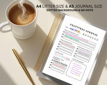 May include: A gratitude journal with a gold spiral binding, a cup of coffee, and a gold pen. The journal is open to a page with the title "Gratitude Journal" and prompts for daily reflections. The text "A4 Litter Size & A5 Journal Size" is at the top.