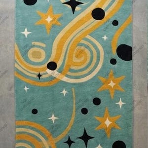 May include: A rectangular rug with a teal background featuring a retro design. The rug has yellow and cream-colored wavy lines, black circles, and star shapes in white, yellow, and black. The rug is a decorative home accent.