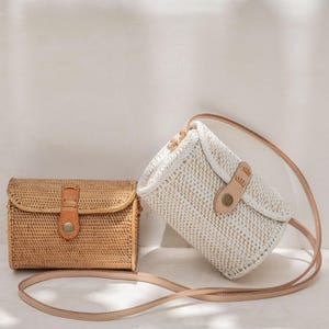 Two handbags, one brown and one white, are placed on a white surface against a white wall.