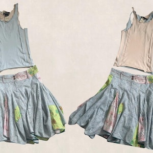 Peut inclure: Deux ensembles : un débardeur bleu clair avec un col festonné et une jupe bleu clair avec des patchworks floraux et verts. Le deuxième ensemble comprend un débardeur beige et une jupe similaire.