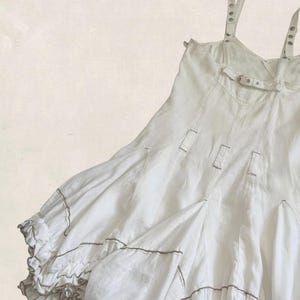 K&ouml;nnte beinhalten: Ein wei&szlig;es &auml;rmelloses Kleid mit d&uuml;nnen Schultertr&auml;gern mit Metall&ouml;sen, einem horizontalen Brustriemen mit Schnalle und vertikalen Bahnen. Der Rock hat einen volumin&ouml;sen, gerafften Saum mit ger&uuml;schten Kanten und feinen grauen Paspeldetails.