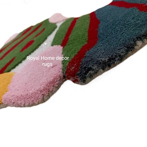 May include: Abstract rug with a textured surface. The rug features a colorful design with sections of green, red, pink, yellow, and blue. The text "Royal Home decor rugs" is visible on the rug.