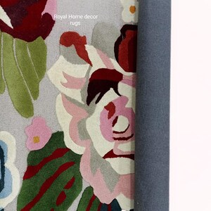 May include: A rolled-up floral rug with a gray backing. The rug features large, colorful flowers in shades of pink, red, green, and white. The text "Royal Home decor rugs" is visible on the rug.